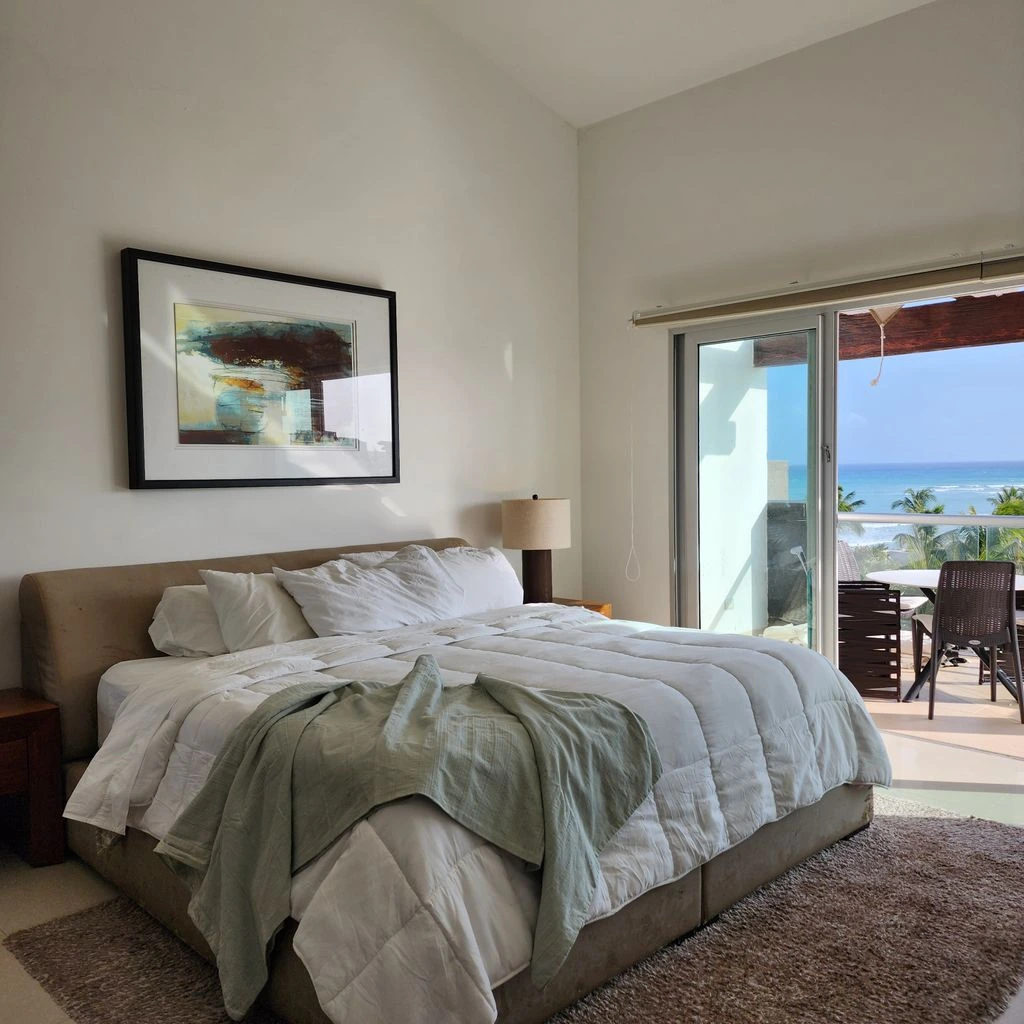 A serene bedroom dressed in oatmeal linen with a walnut bed and cane headboard.